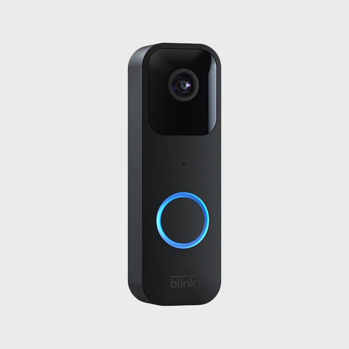 Doorbell camera emits blue ring light indoors on plain background. Text reads 