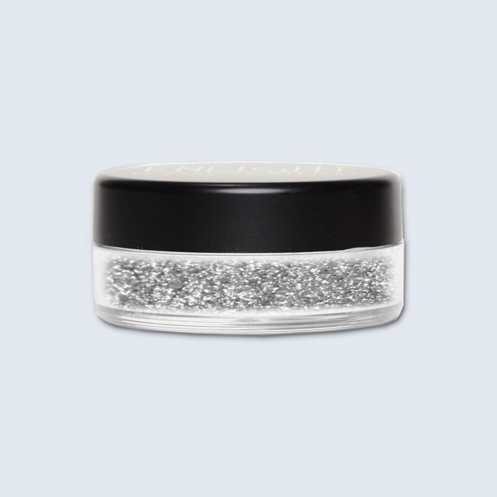 A round container holds silver glitter, topped with a black lid, set against a plain light background.