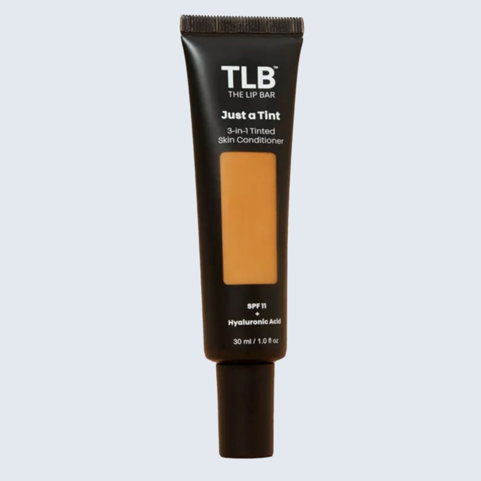 Tube displays tinted skin conditioner text with SPF 11, hyaluronic acid benefits, in black packaging, positioned against a light background.