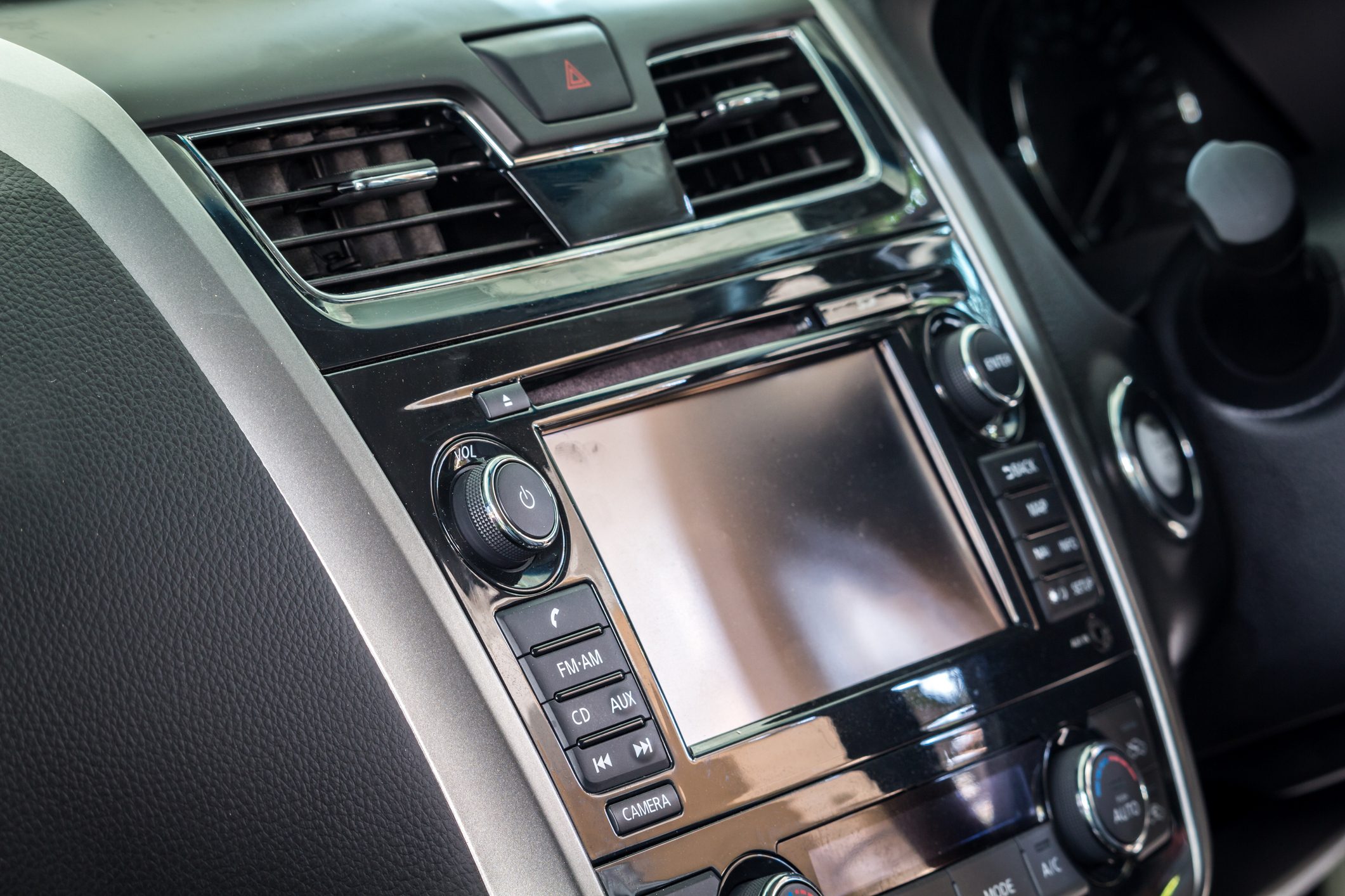 Car dashboard with a touchscreen display, surrounded by control knobs and buttons, set in a sleek, modern interior.