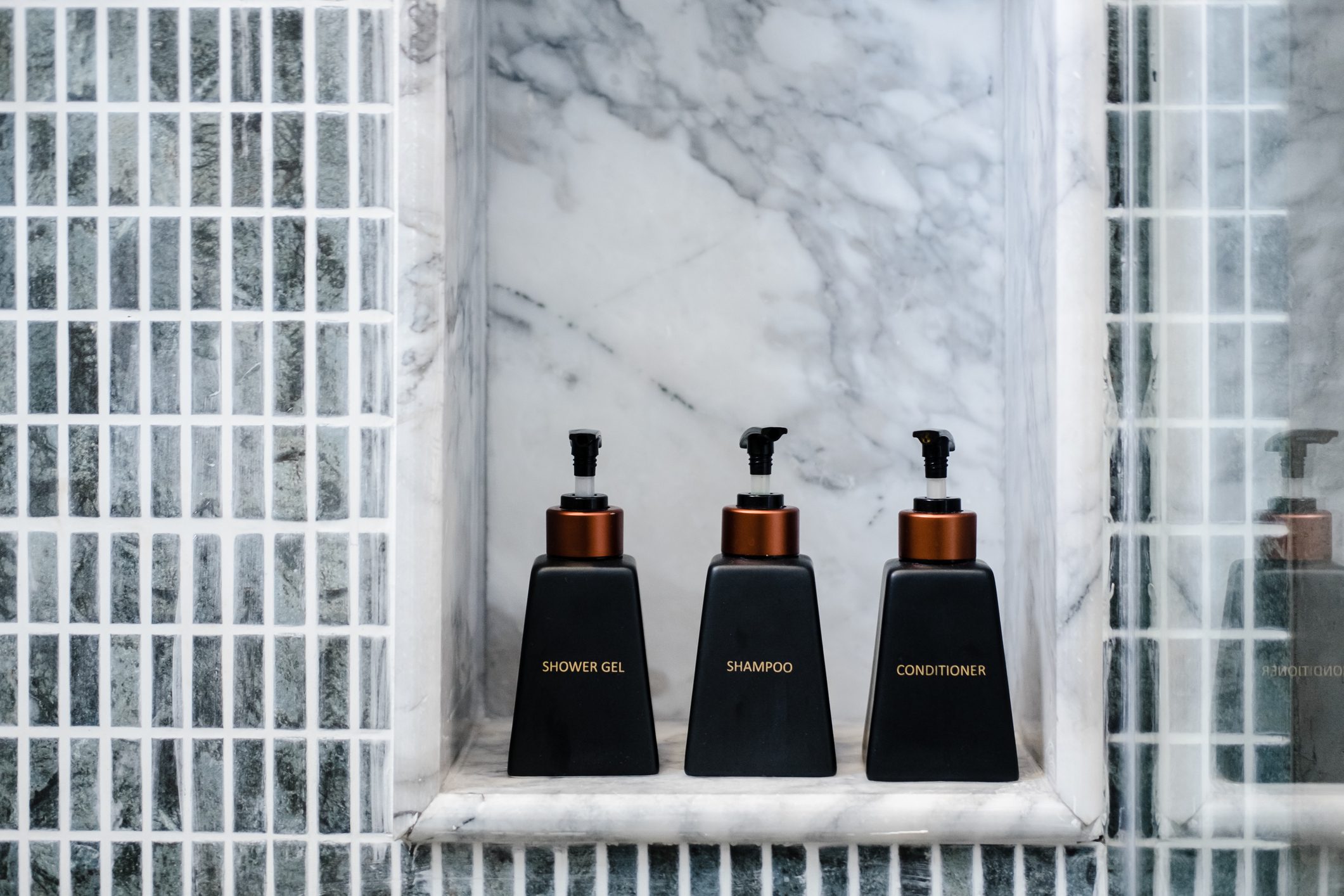 Bathroom toiletries on marble shelf in a hotel shower