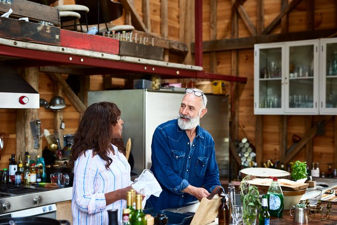 Mature couple talking in kitchen and doing the dishes