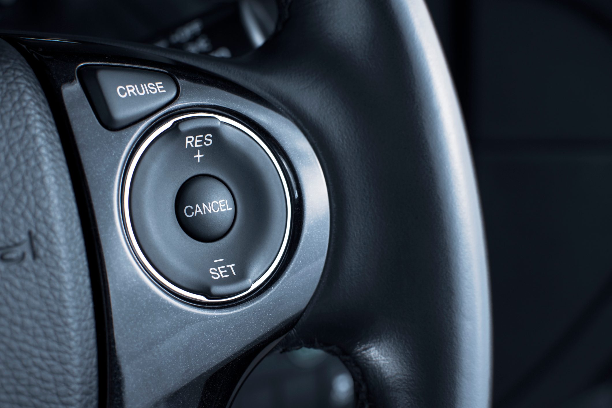 Steering wheel with cruise control buttons labeled "CRUISE," "RES +," "CANCEL," and "SET" in a car interior.