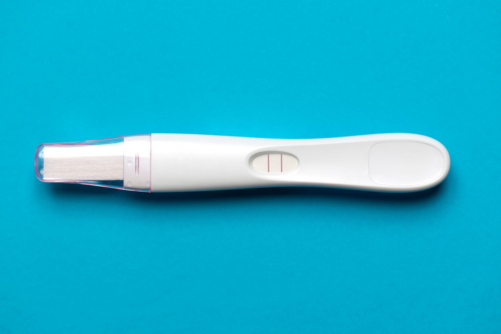 Pregnancy test shows two lines, placed on a bright blue background, indicating a positive result.