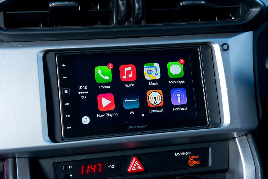 Touchscreen displays apps in car dashboard; visible apps include Phone, Music, Maps, Messages, Podcasts. Time shows 11:48 with cellular signal and 3G.