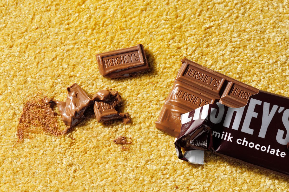 melted chocolate bar creating a chocolate stain on a yellow carpet