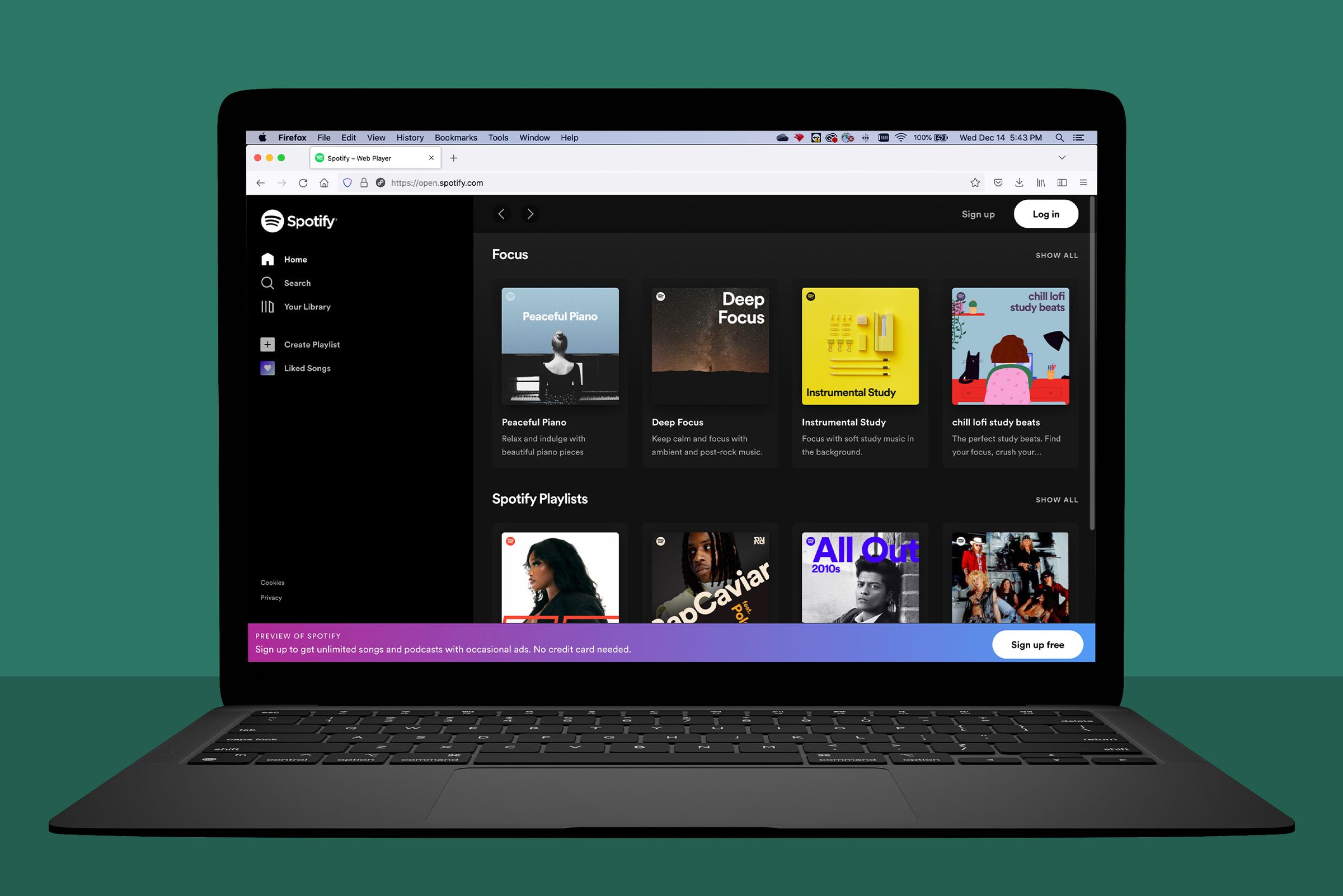 Laptop displaying Spotifyâ€™s web interface; showing music playlists under "Focus" category against a green background.