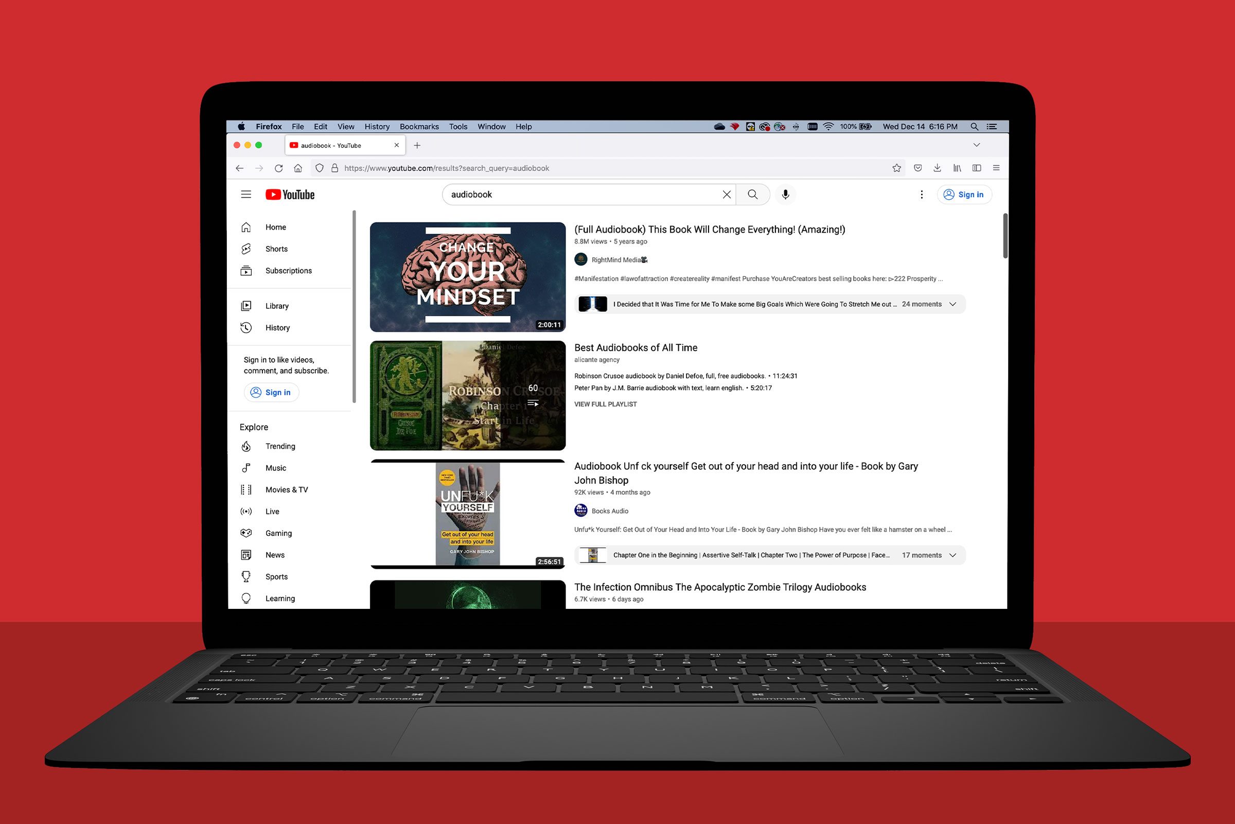 A laptop displays YouTube search results for "audiobook," against a red background. Videos include "Change Your Mindset" and "Best Audiobooks of All Time."