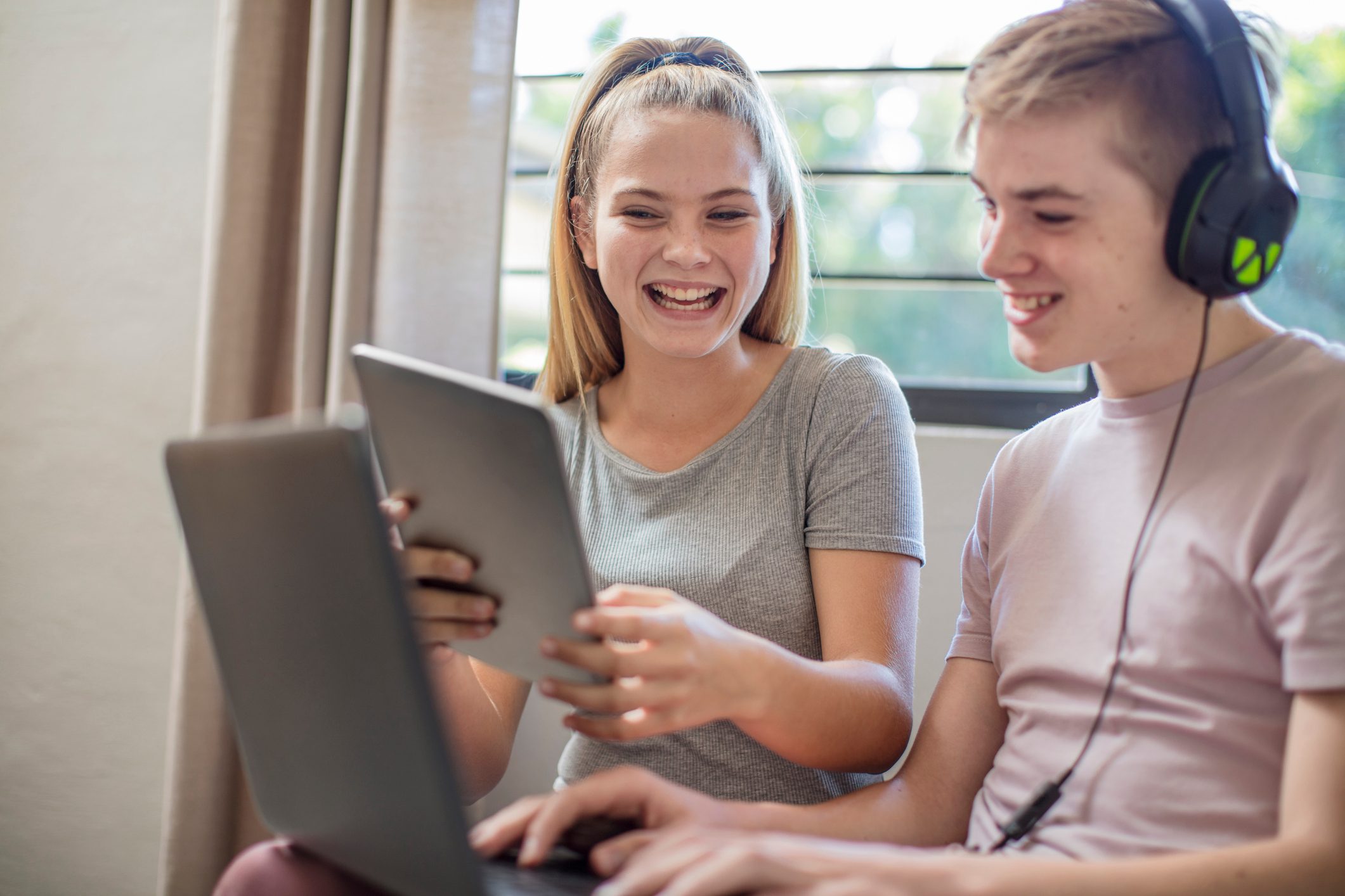 Happy boy and teenage girl with tablet, laptop and headphones