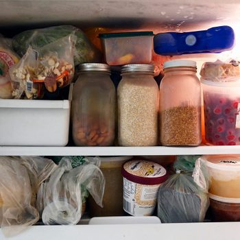 A freezer storing various foods: jars of grains, containers with berries and ice cream, and plastic bags, all neatly organized on shelves.
