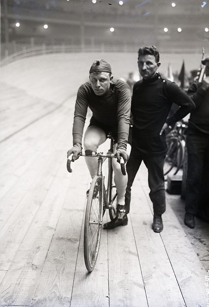 Two Men One On A Bike Other Standing