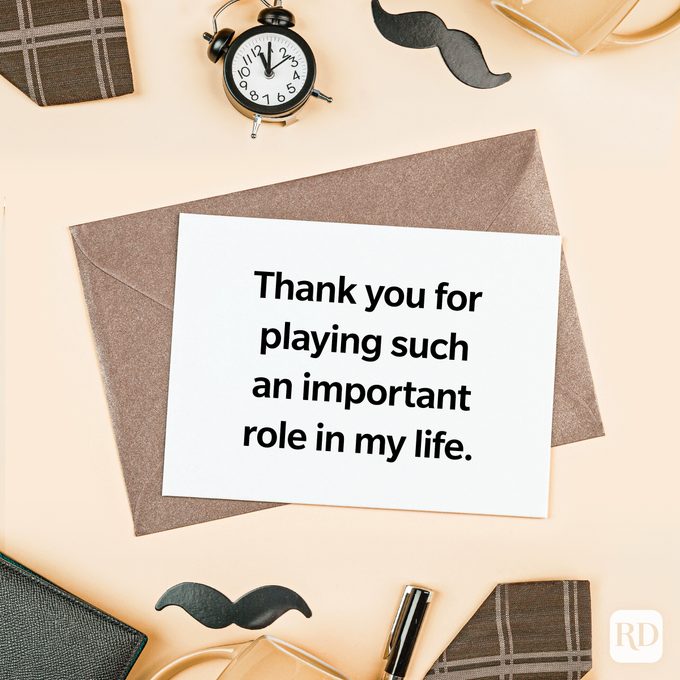 Card displays gratitude, lying on a brown envelope. Surrounding objects: a clock, mustache cutouts, and a pen, creating a thoughtful setting.