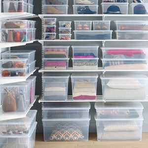 Clear plastic boxes organize clothes and accessories on white shelving within a neatly arranged closet space.