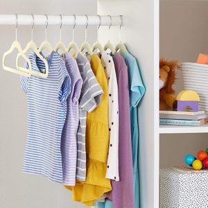 Children's clothes hang neatly in a closet, surrounded by a shelf with a lion plush, books, toys, and a patterned box.