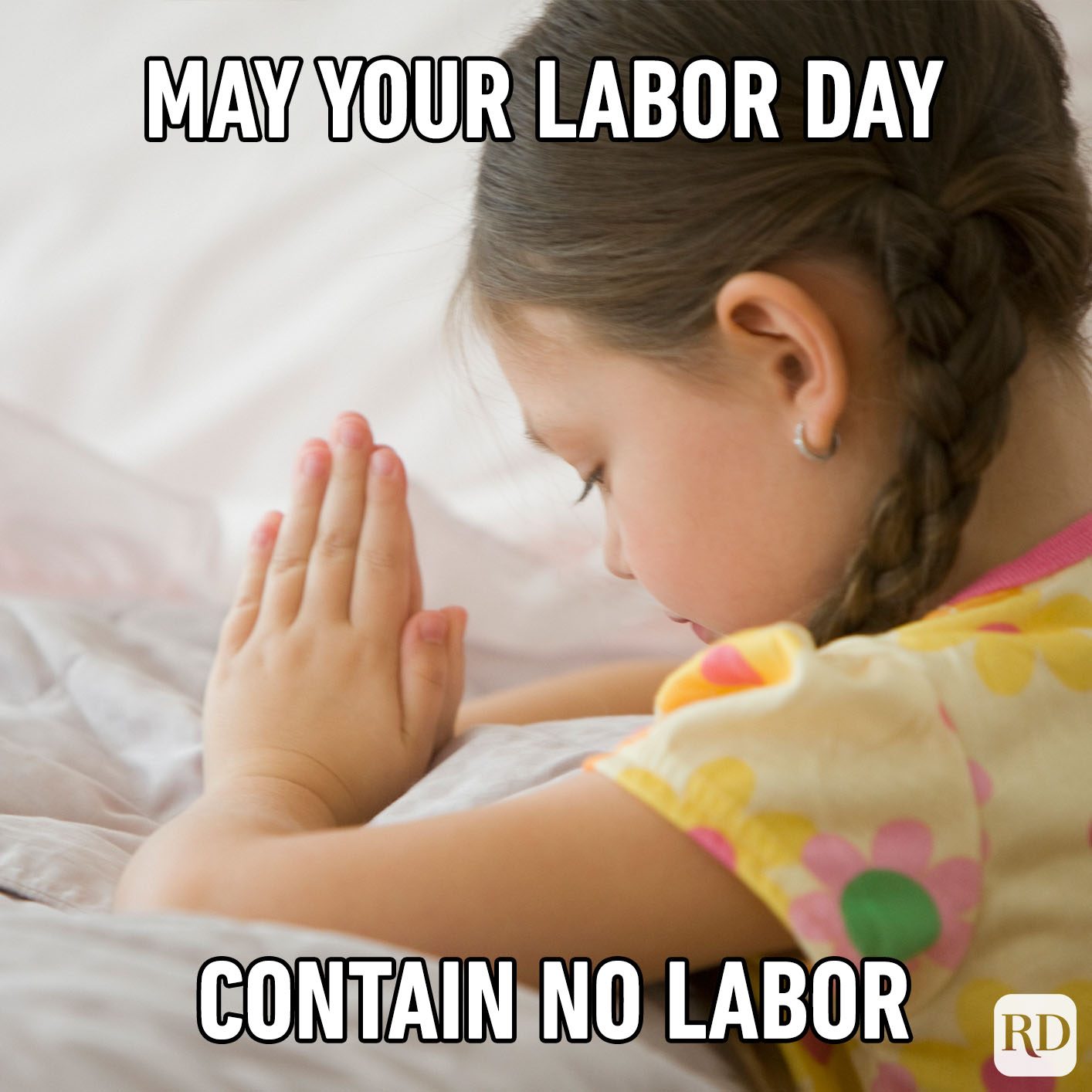 Child prays silently on bed; text above reads "May your Labor Day contain no labor."