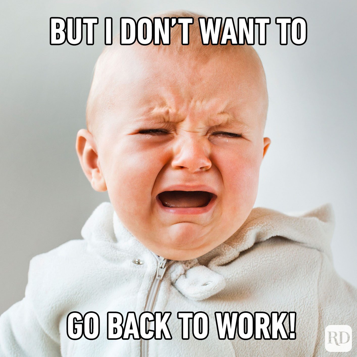 Baby crying, wearing a white outfit, with text saying, "BUT I DON'T WANT TO GO BACK TO WORK!" in a neutral background.