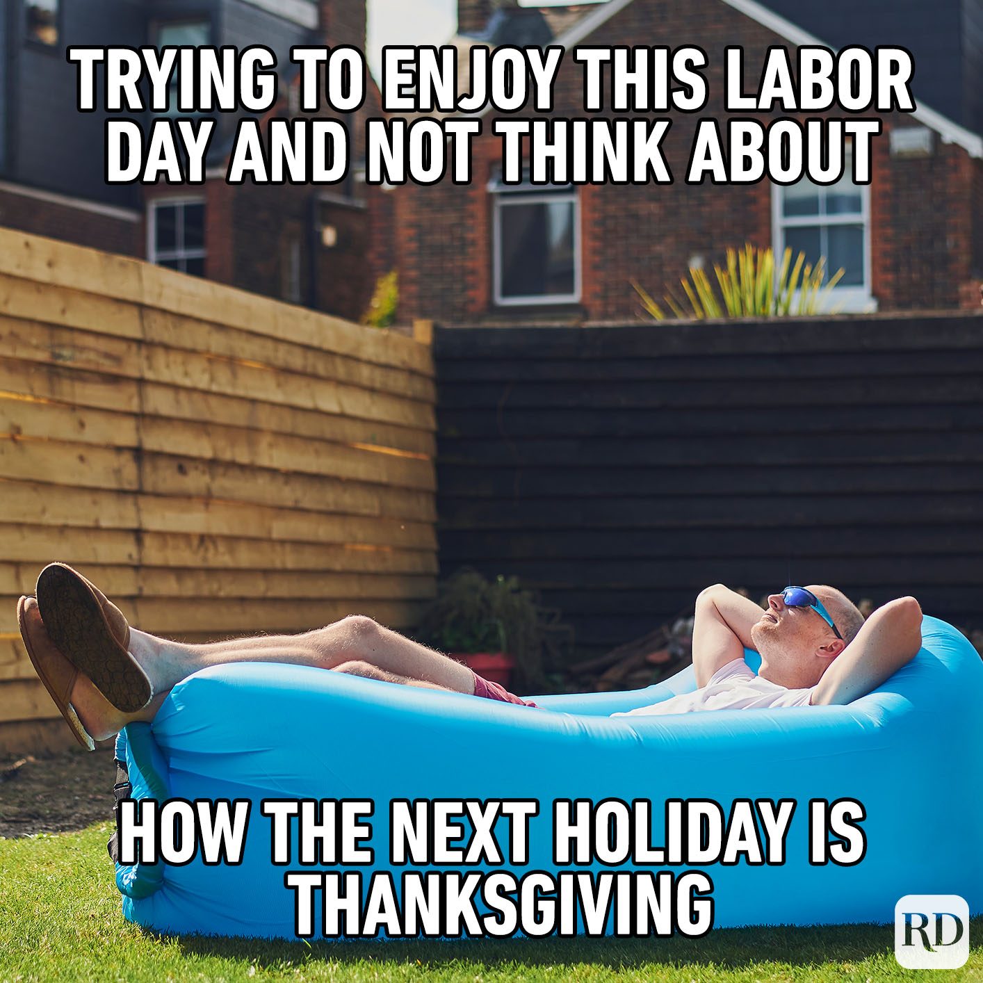 Man relaxes on blue inflatable lounger outdoors; text humorously addresses Labor Day and upcoming Thanksgiving.