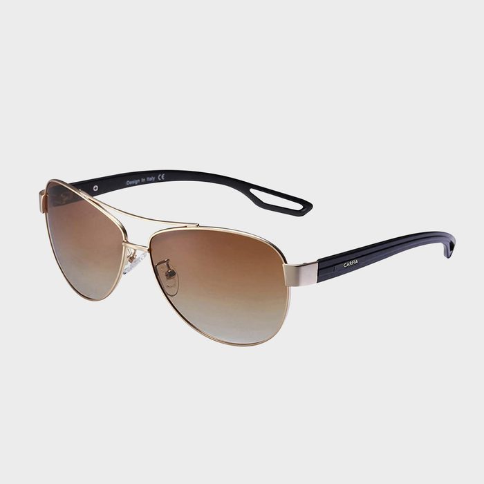 Sunglasses rest on a white background, featuring gold frames, brown gradient lenses, and black arms with 