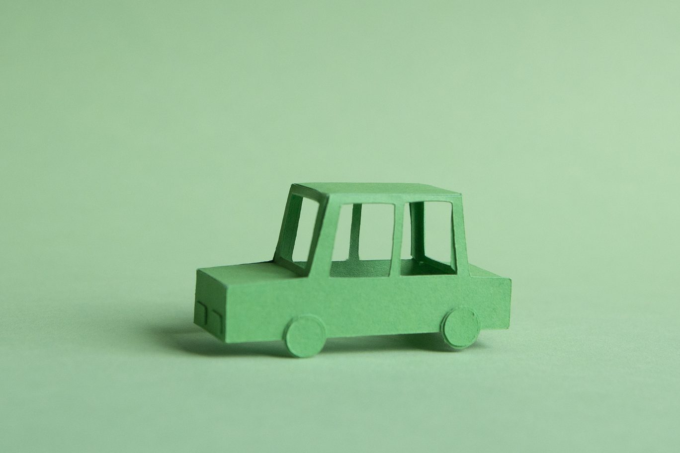 Paper car made of green paper on green background