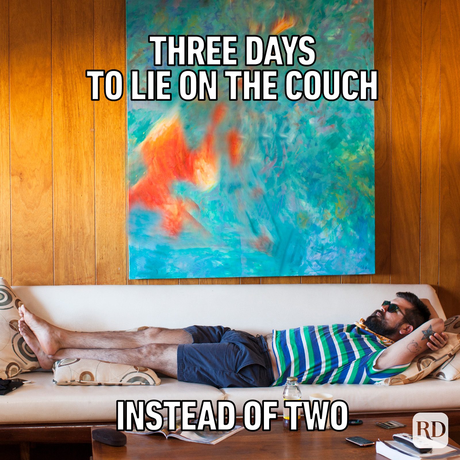 Man lies on couch, relaxing in a room with wooden walls and abstract painting. Text reads: "Three days to lie on the couch instead of two."