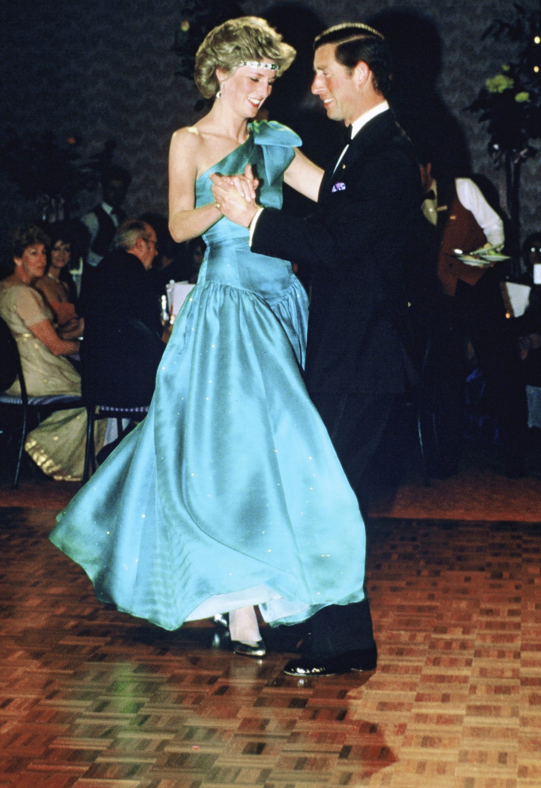 Prince Charles, Prince of Wales and Diana, Princess of Wales, wearing a green satin evening dress designed by David and Elizabeth Emanuel and an emerald necklace as a headband, dance together during a gala dinner dance at the Southern Cross Hotel on October 31, 1985 in Melbourne, Australia.