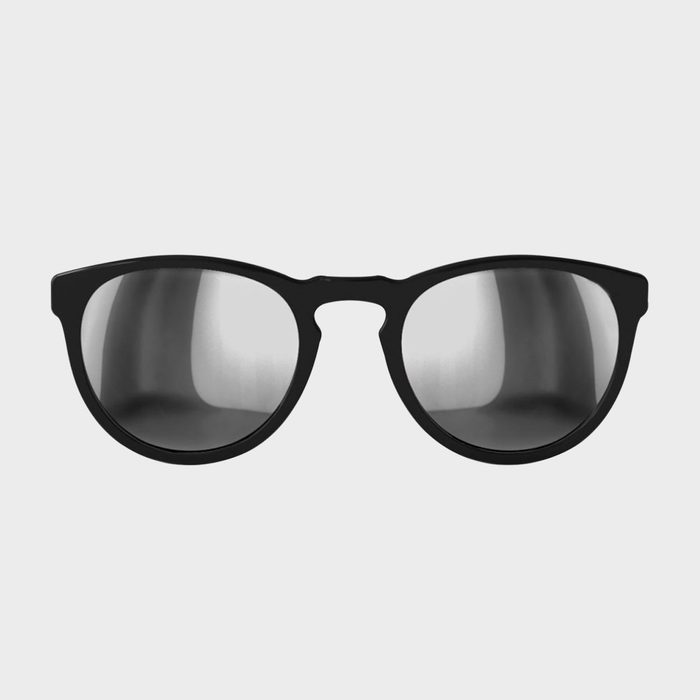 Black sunglasses reflect light, sitting against a plain white background.