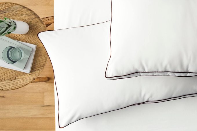 Saatva Latex Pillows on a bed next to a wood table