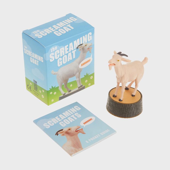 A goat figurine stands on a base, surrounded by a blue box and booklet titled 