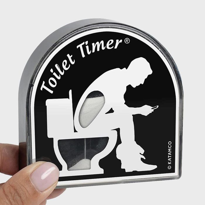Timer shaped like a toilet, shows a person sitting and using a phone; held by a hand. Text: 