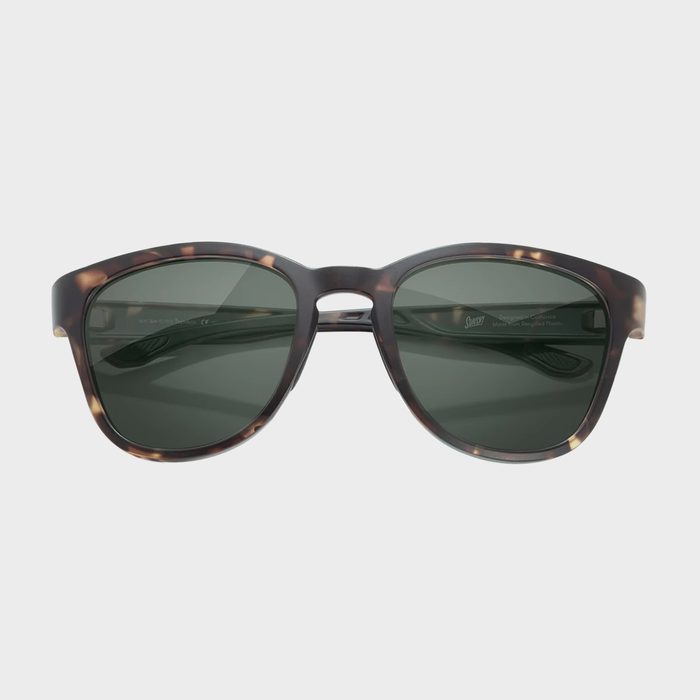 Tortoise-shell sunglasses resting upright, displaying dark green lenses against a plain white background.