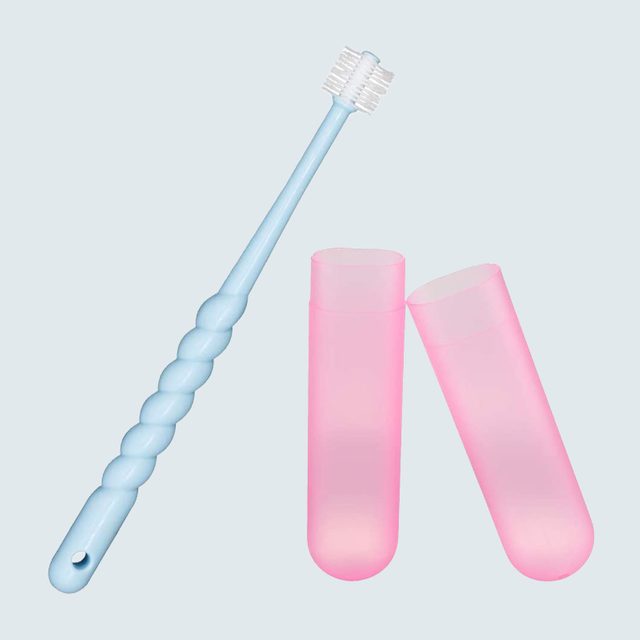 A light blue toothbrush rests near two open pink cases on a pale background.