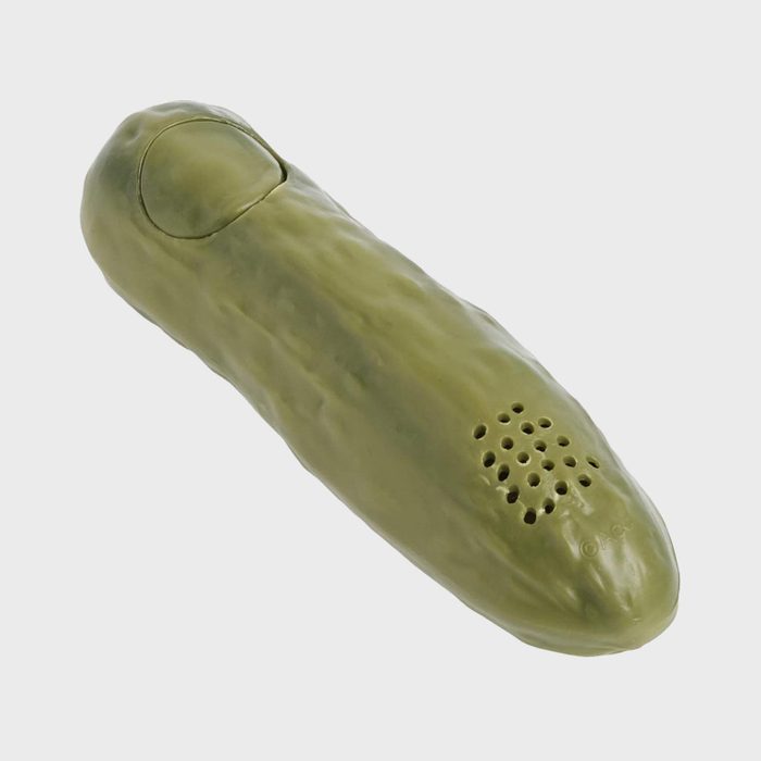 Green pickle-shaped speaker rests on a plain surface, featuring vent holes and a visible power button, set against a white background.
