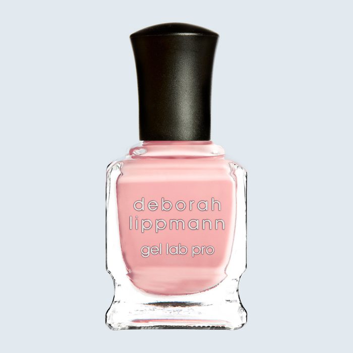 Pink nail polish sits in a clear bottle with black cap and 