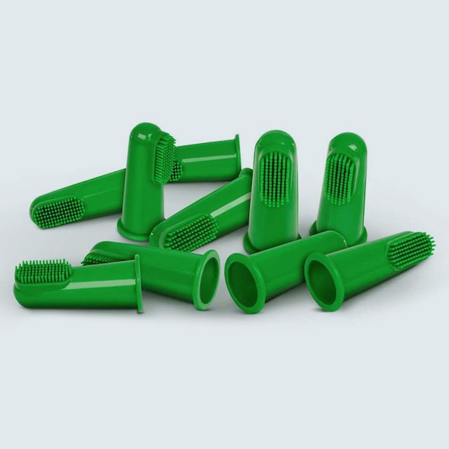 Green silicone finger toothbrushes, scattered, on a plain, light background.