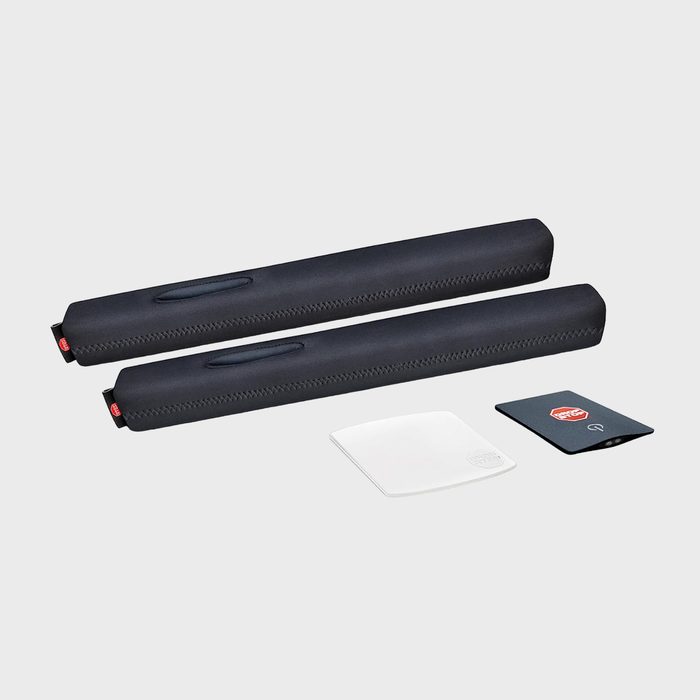 Two black padded items lie side by side; nearby are two square patches, one white and one dark, on a gray background.