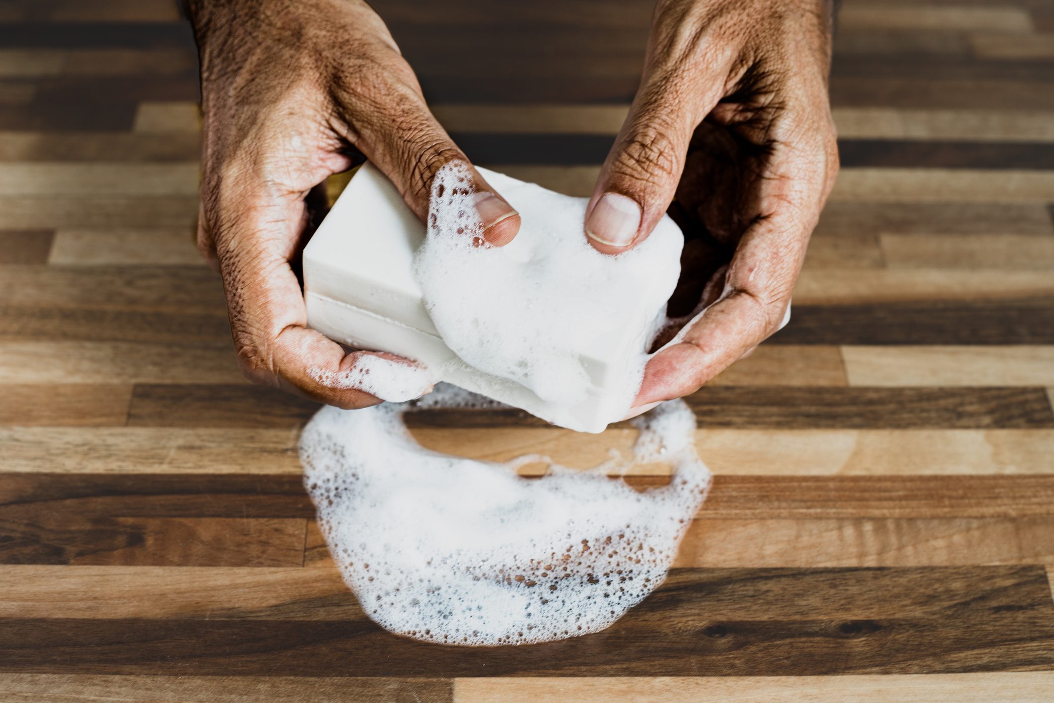 An old man washing his hands with a bar of soap