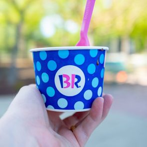 A hand holds a polka-dotted blue cup with 