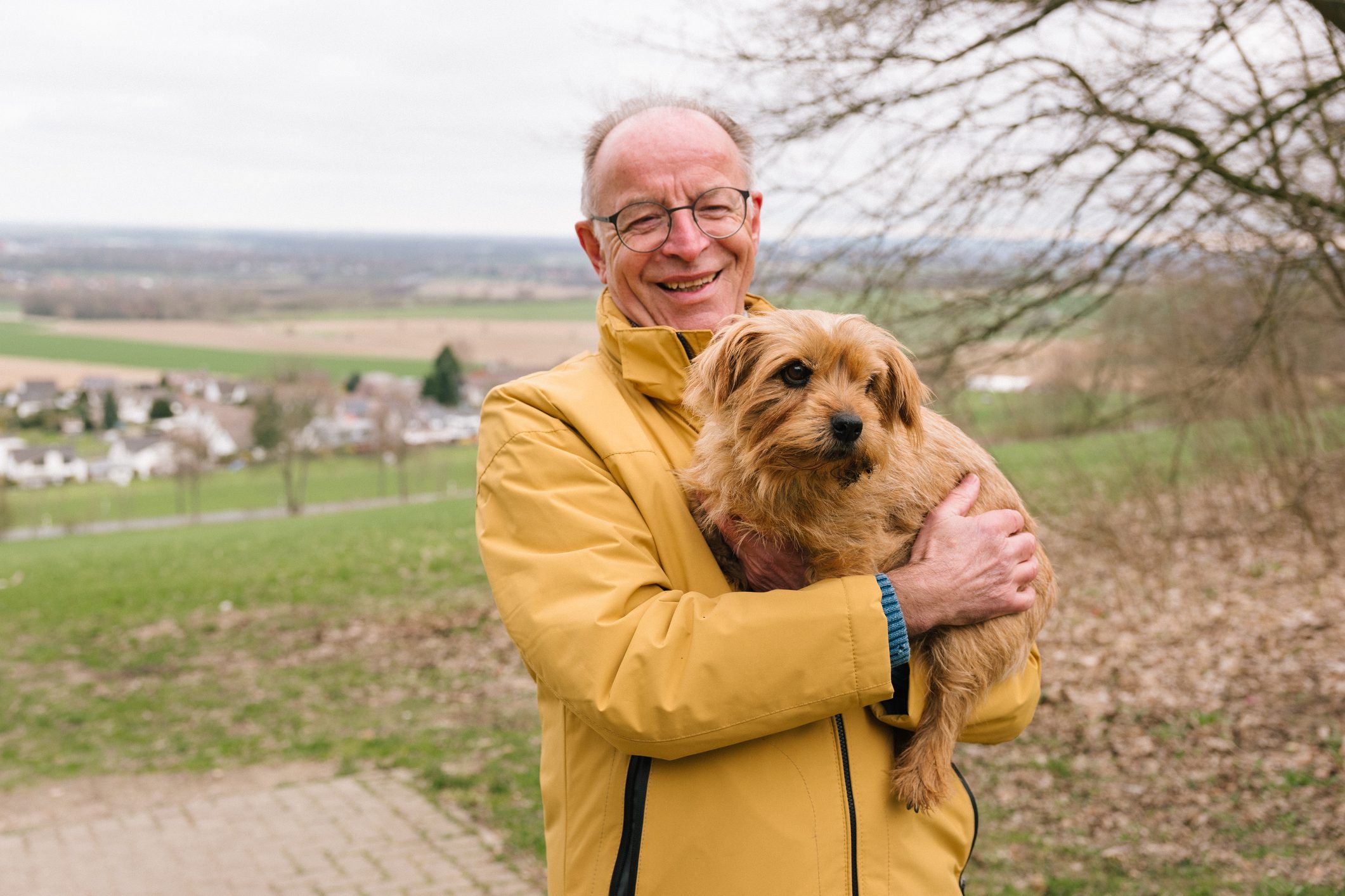 portrait of man holding his norfolk terrier dog outside