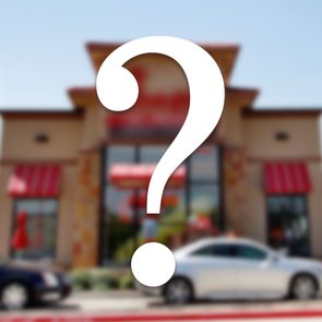 A large question mark overlays a blurred image of a fast-food restaurant with red-striped awnings and parked cars in a sunny setting.