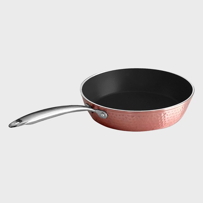 Copper-colored frying pan with a shiny metal handle, resting against a plain light gray background.