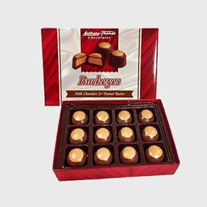 Box of buckeye chocolates, arranged in rows, sits inside open red packaging labeled 