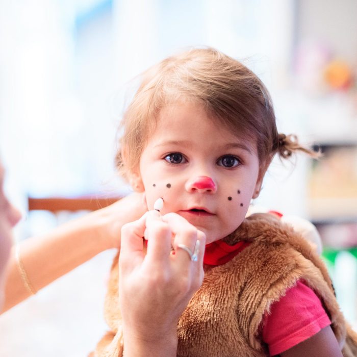 mom putting dog makeup on her child for halloween
