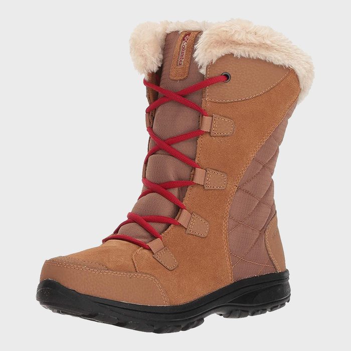 Boot stands upright, showcasing soft tan fabric with red laces, black sole, and fluffy cream lining in a studio setting.