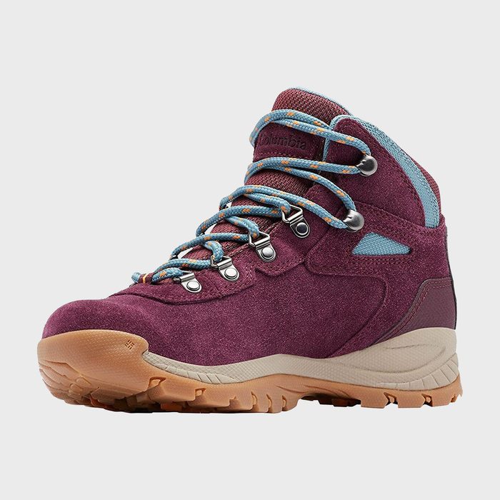 A maroon hiking boot with blue laces resting on a light gray background, highlighting its rugged tan sole and metal eyelets.