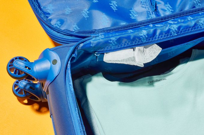 dryer sheet poking out of the lining zipper in an open suitcase