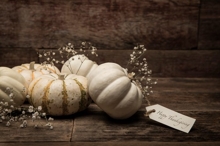 White pumpkins with delicate flowers rest on wooden boards; a tag reads 