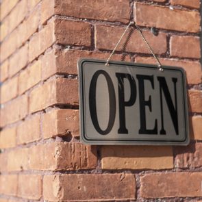 Sign hangs on brick wall, displaying 