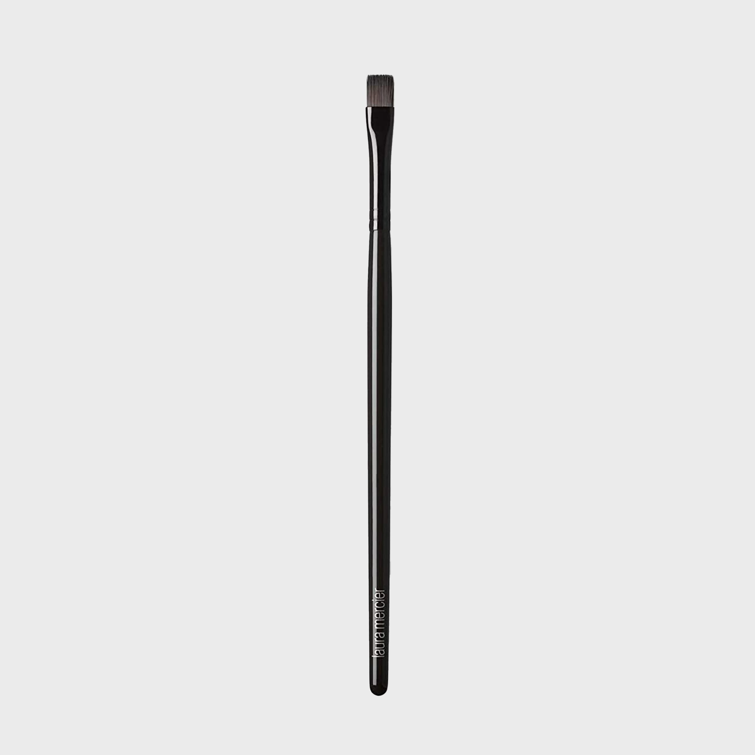 A black makeup brush stands upright against a plain white background.