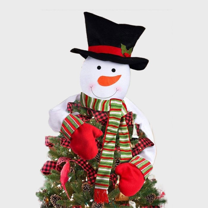Snowman topper decorates Christmas tree, wearing a black hat, red mittens, and striped scarf amidst pine cones and string lights.