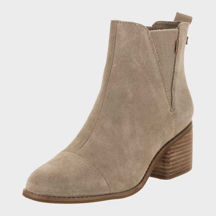 A suede ankle boot with stacked heel stands on a blank white background.